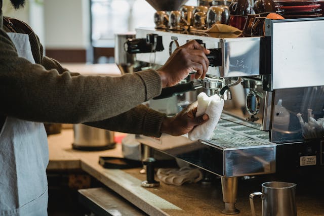 Barista cleaning a café coffee machine and counter area