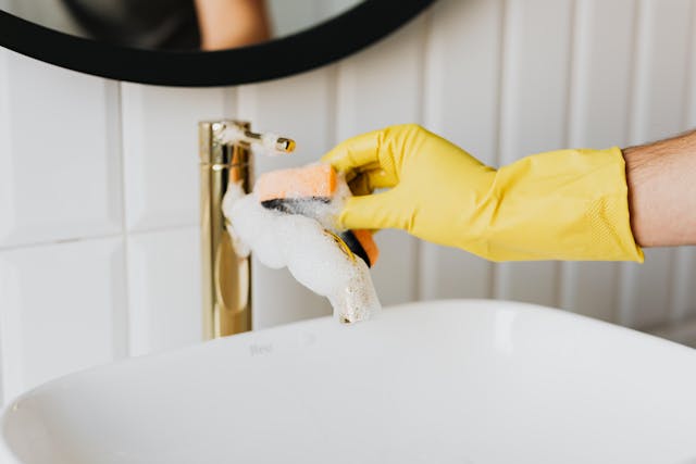 Residential bathroom cleaning with gloves and a sponge at the sink
